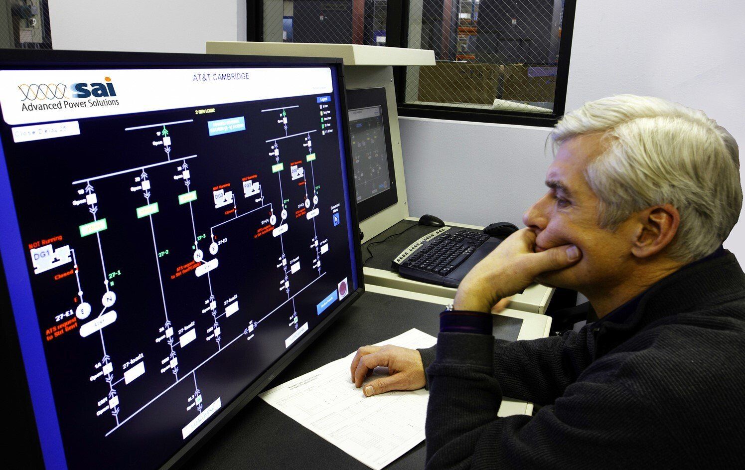 A man is sitting in front of a computer monitor with a screen that says nsd sai on it
