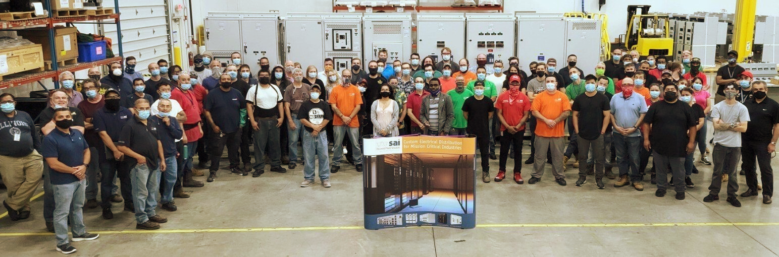 A large group of people are standing in a warehouse.