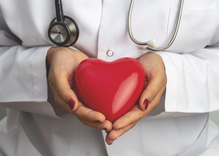 Doctor holding a red heart-shaped object with a stethoscope around the neck