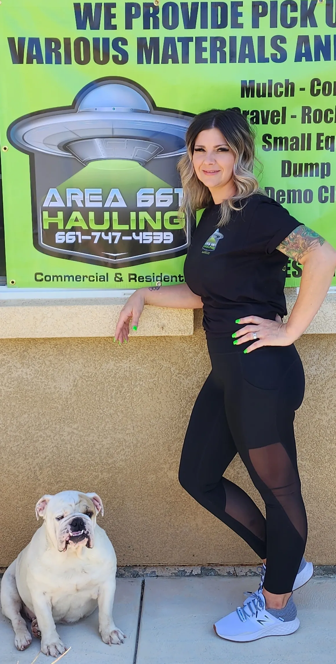 A woman is standing next a Area 661 Hauling sign.
