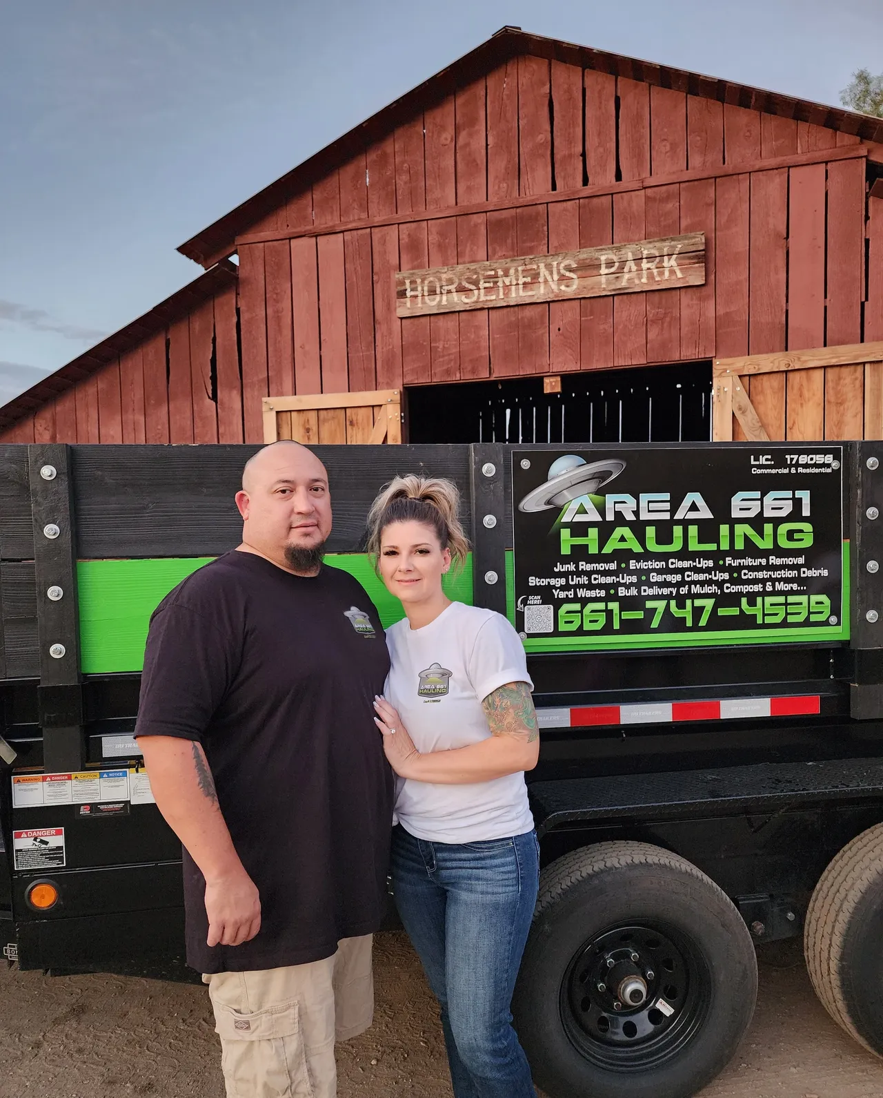 A man and a woman are standing in front of a trailer that says area 661 hauling