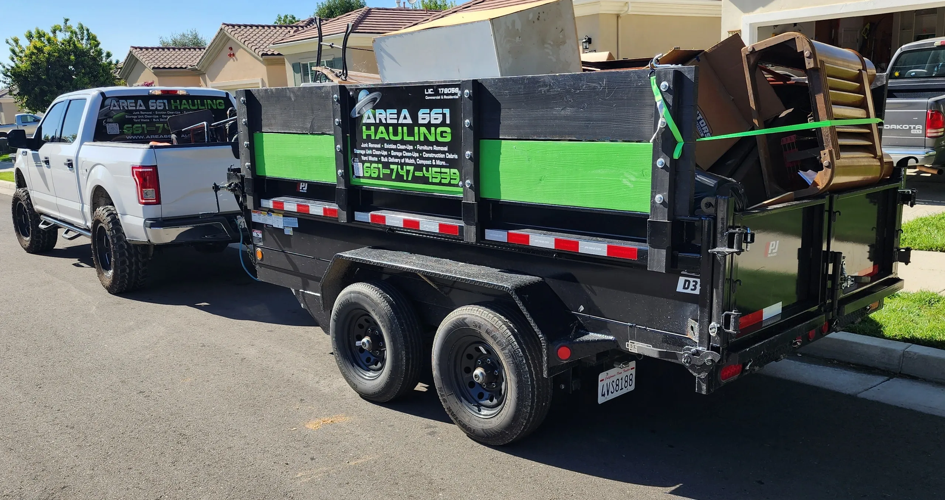 A dumpster full of junk is being pulled by a truck on a trailer.
