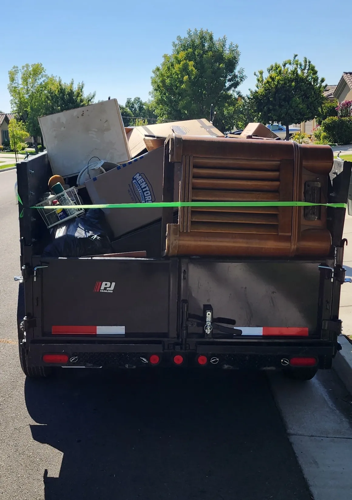 A trailer filled with furniture is being hauled off. 