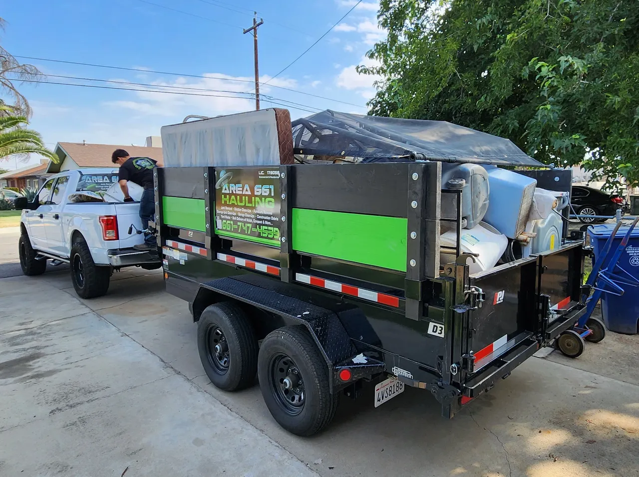 A dumpster trailer is being towed by a white truck full of trash.