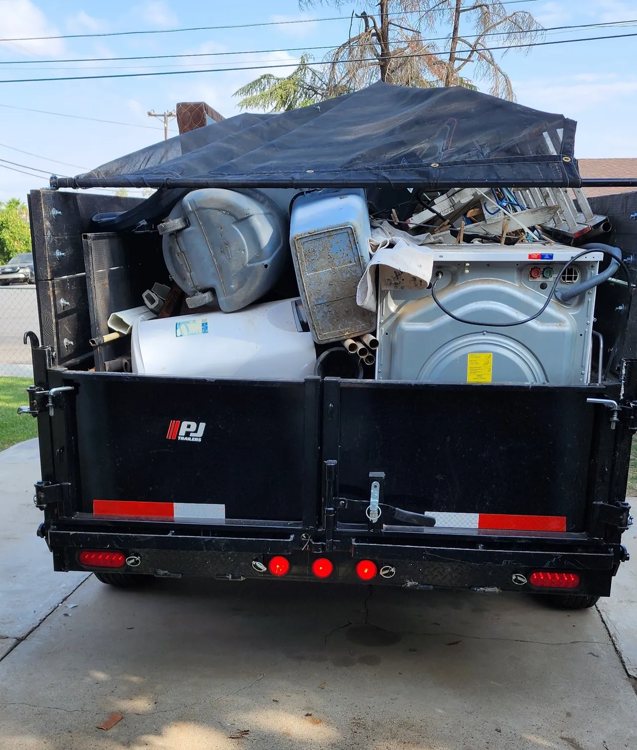 A dumpster with a washer and dryer in it being taken to the waste station