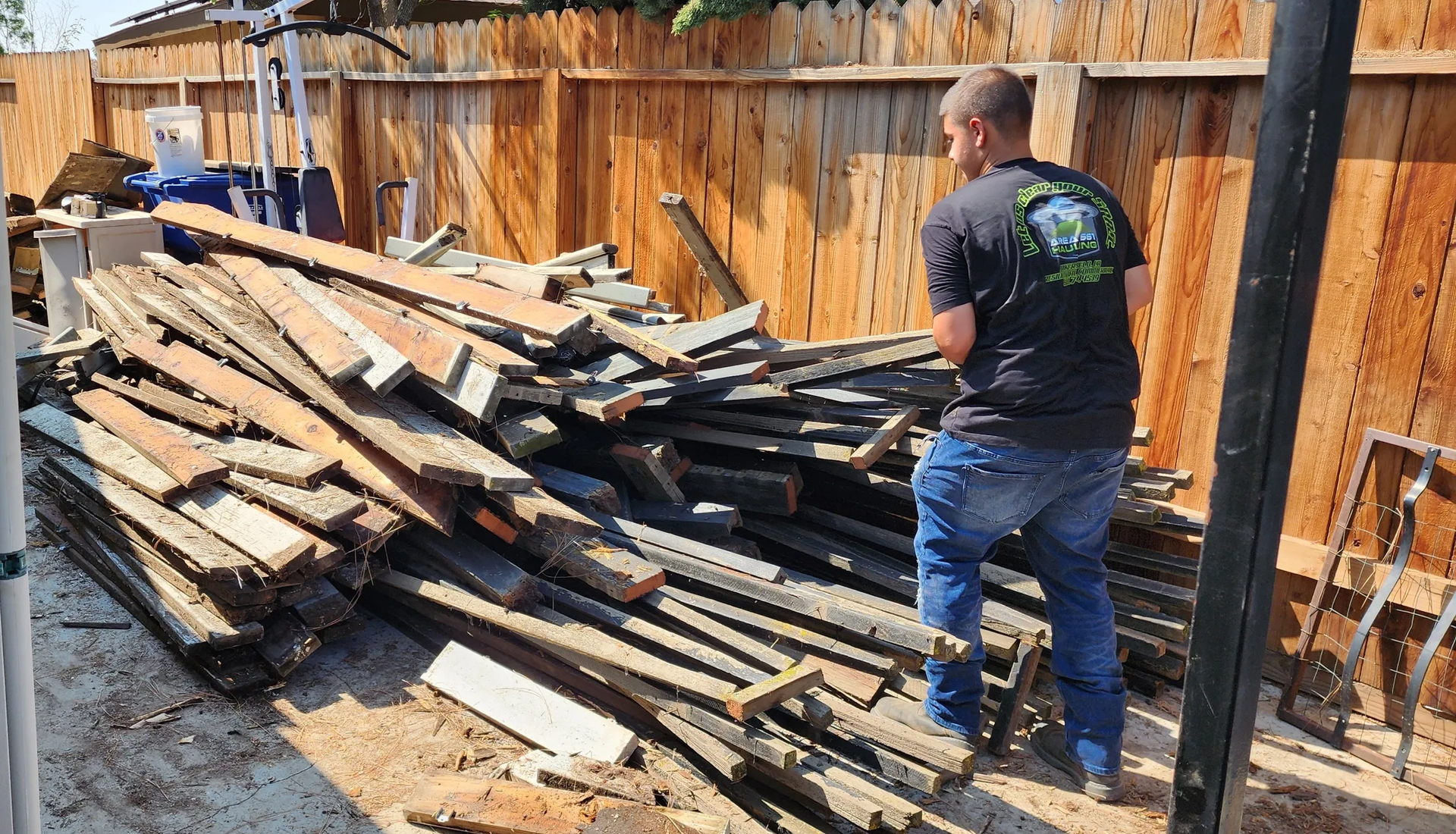 A man hauling off a pile of wood from a yard in Bakersfield, CA.