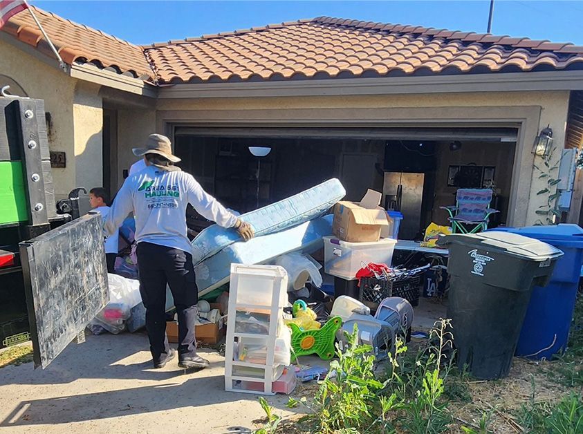 A man is standing in front of a garage full of junk.