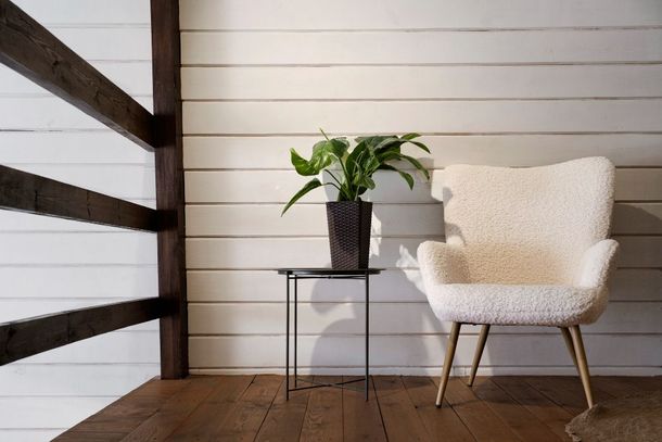 A white chair is sitting next to a small table with a potted plant on it.