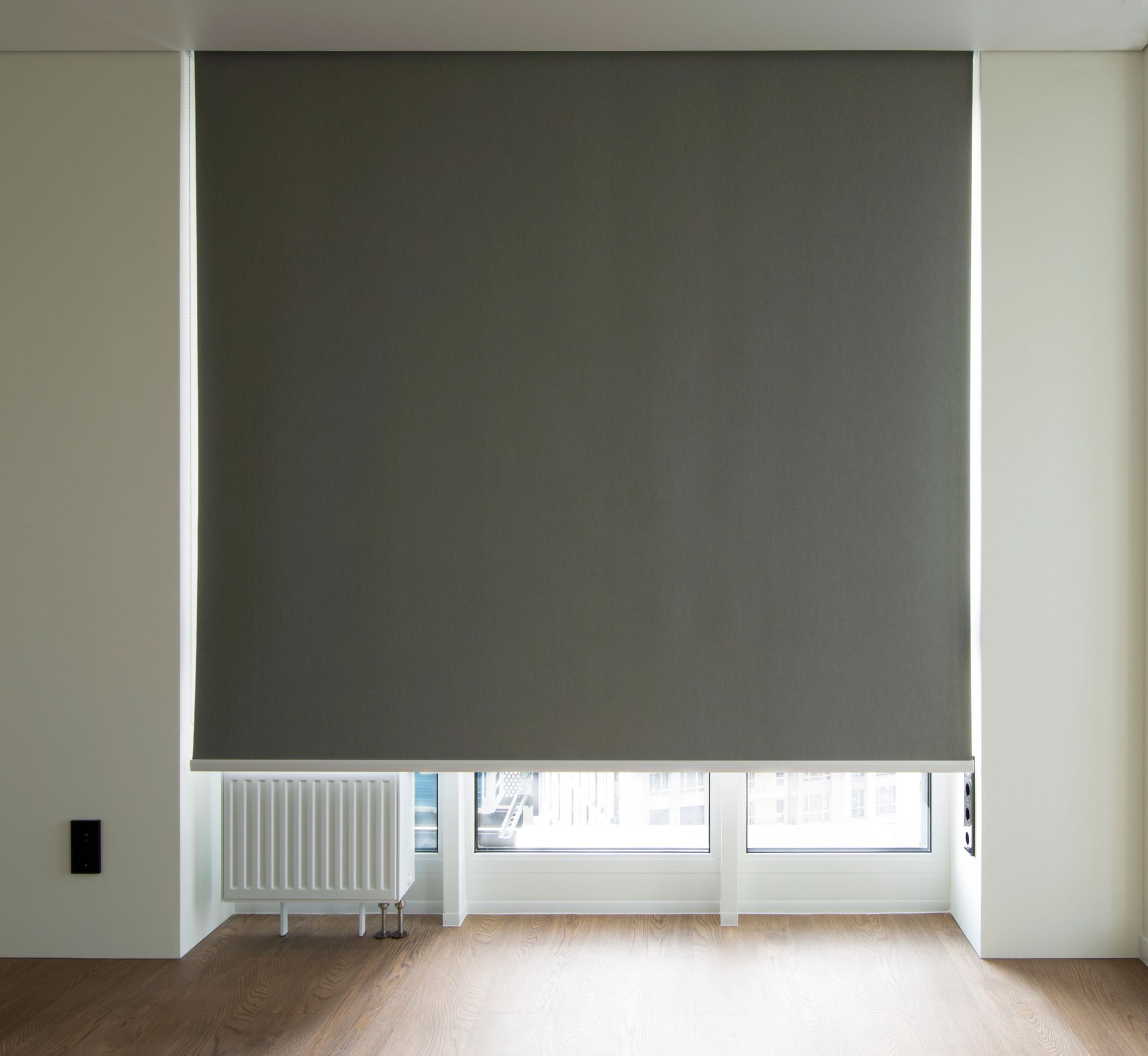 Una persiana enrollable gris cubre parcialmente una ventana
