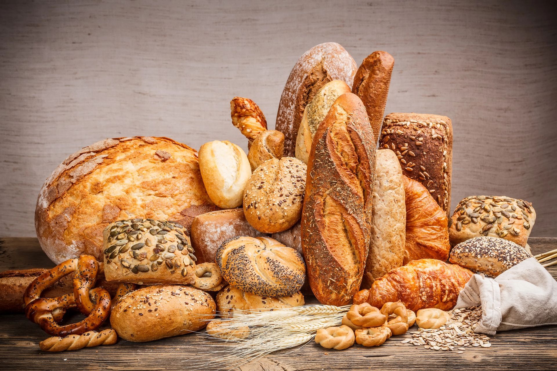 Pane e pasticceria freschi assortiti, disposti su un tavolo rustico con uno sfondo neutro