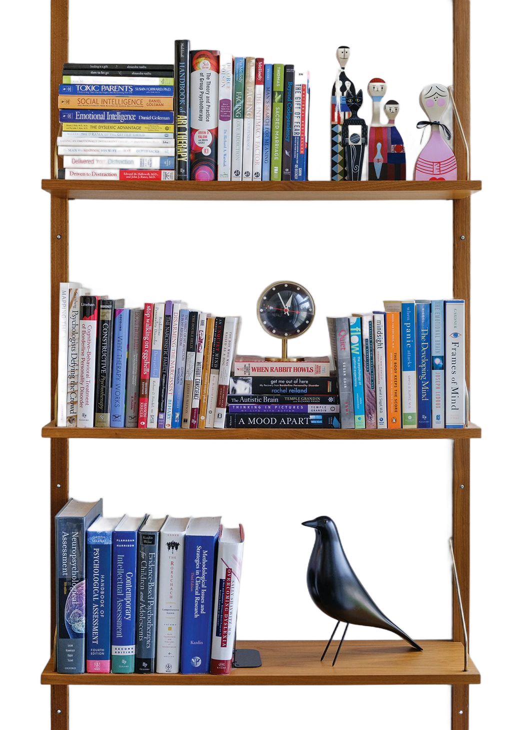 Wooden bookshelf with colorful books and small figurines, including a black bird sculpture on the bottom shelf