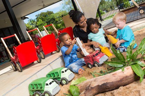 Woman with Kids Playing Toy Trucks — Darwin, NT — Territory Child Care Group