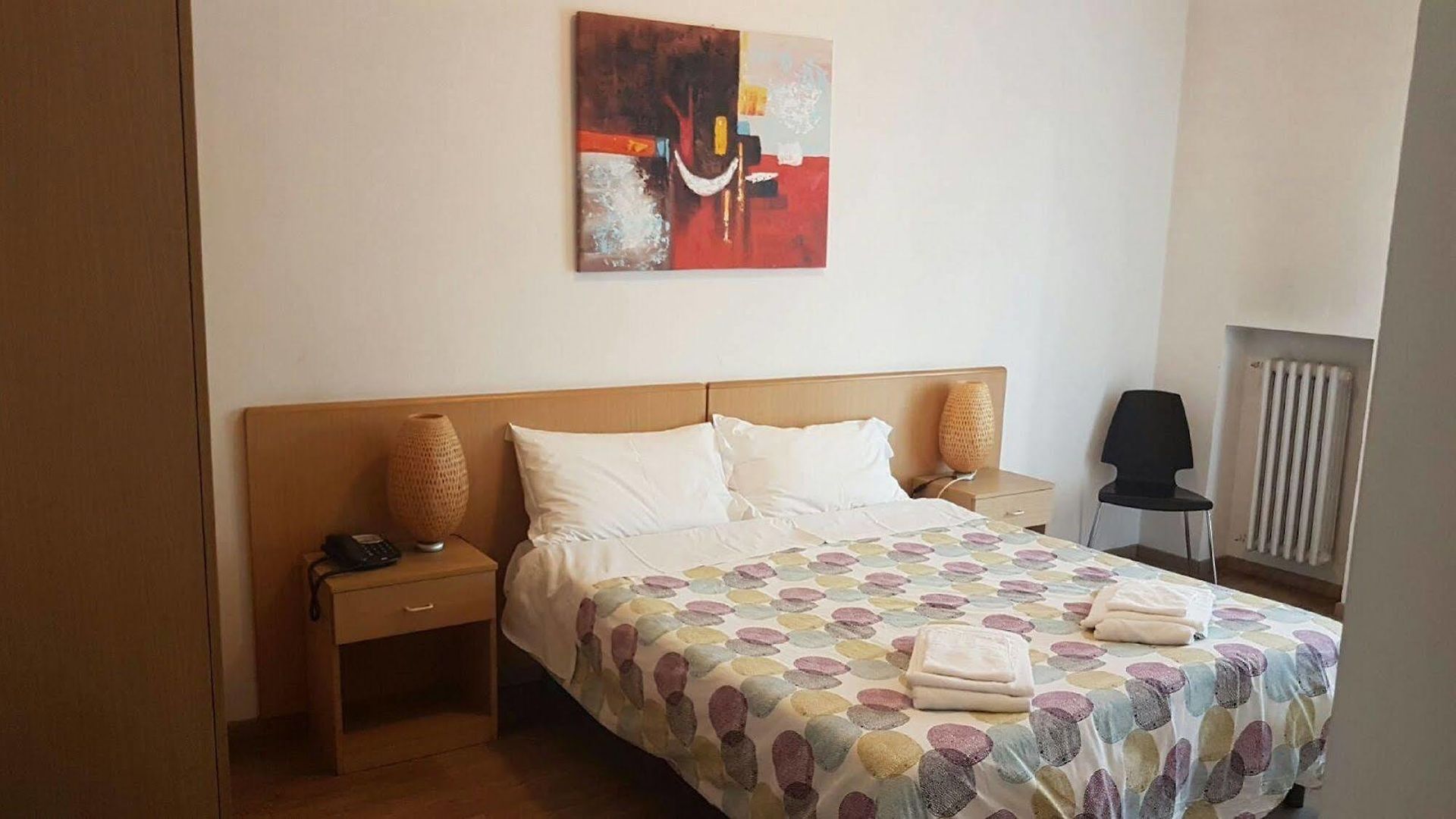 C'è un dipinto sul muro sopra il letto nella stanza.