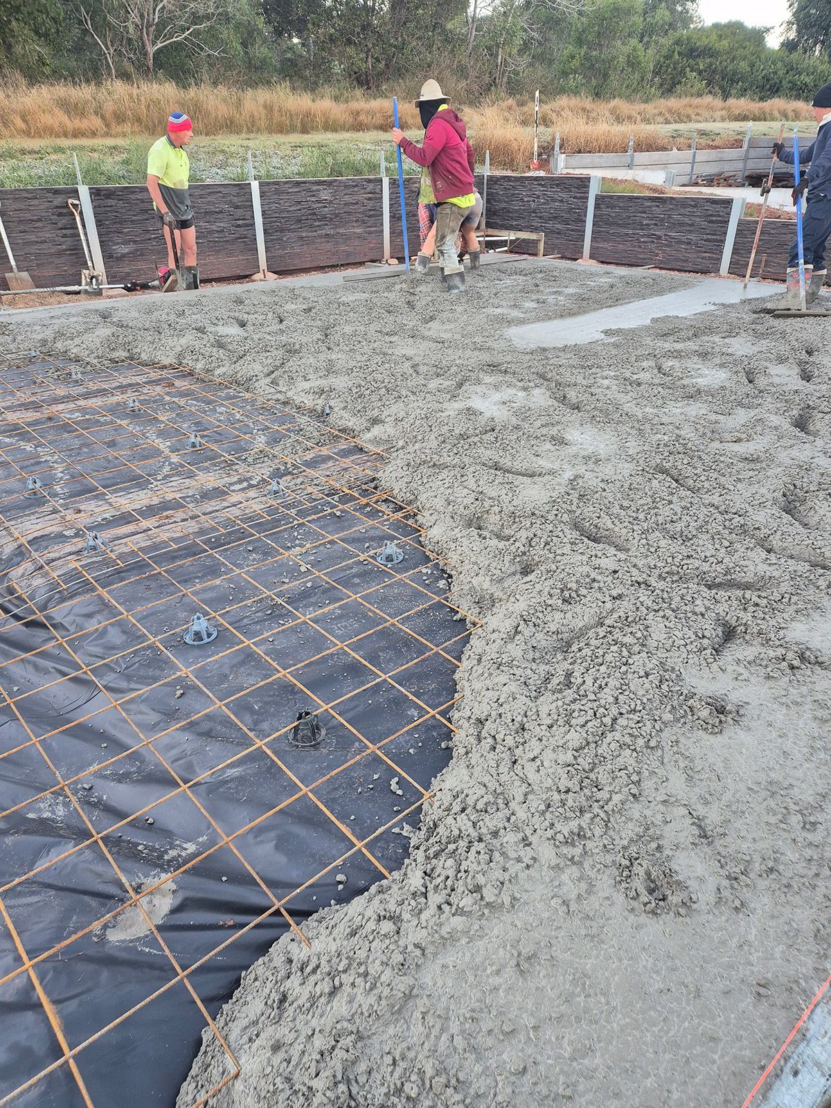 Workers Pouring Concrete Over Rebar at a Construction Site — TP Concreting In Warilla, NSW