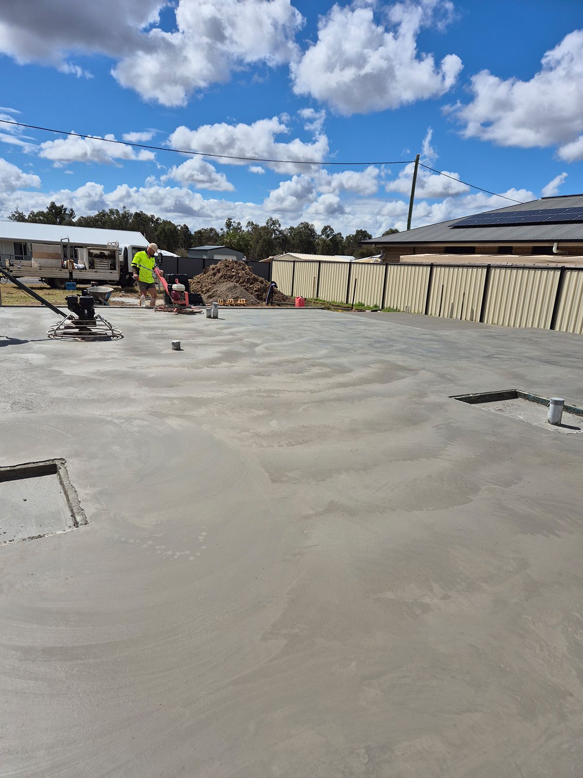 Freshly Poured Concrete Slab With Workers, Utility Vehicle, and a Building — TP Concreting In Warilla, NSW