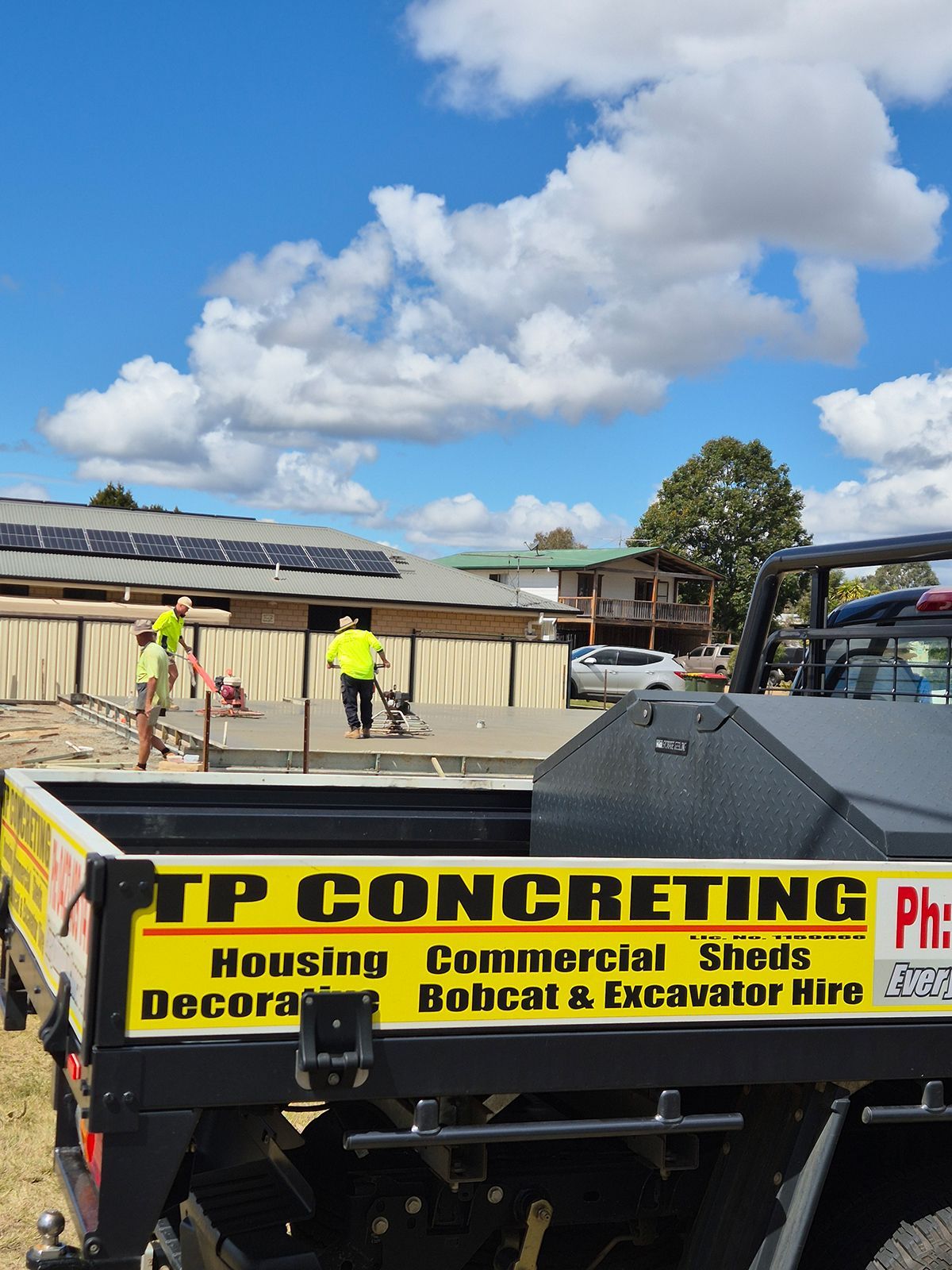 Workers Install Solar Panels on a Roof Beside a Tp Concreting Truck Under a Blue Sky — TP Concreting In Warilla, NSW