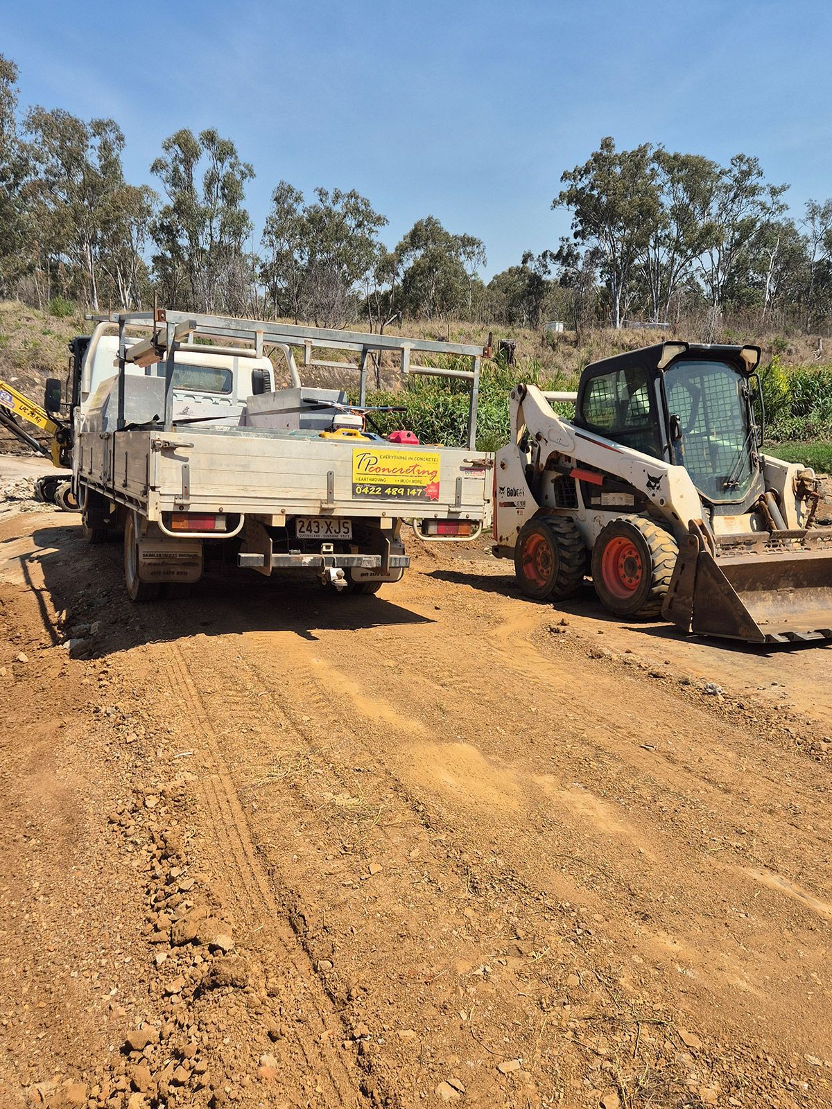 White Utility Truck and Skid Steer on a Dirt Road at a Rural Worksite — TP Concreting In Warilla, NSW