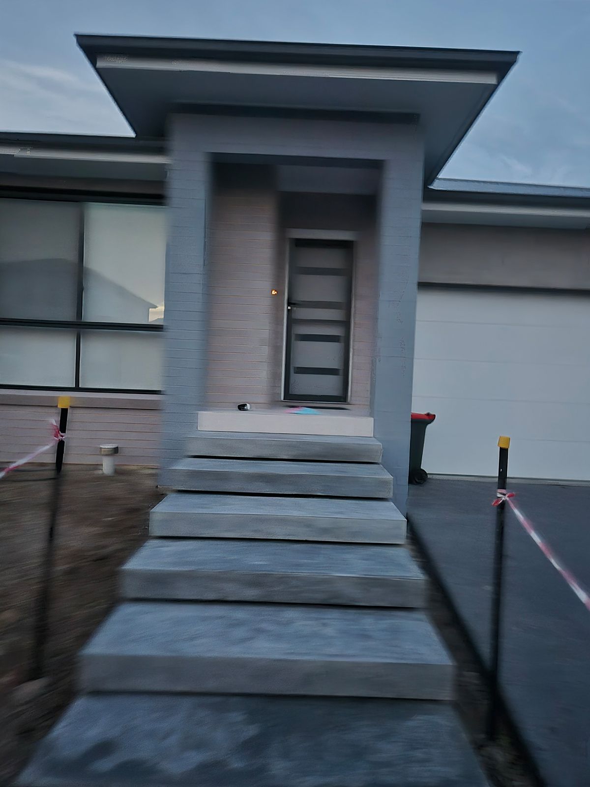 Modern House Entrance With Concrete Steps, a Covered Porch, and Wet Pavement — TP Concreting In Warilla, NSW