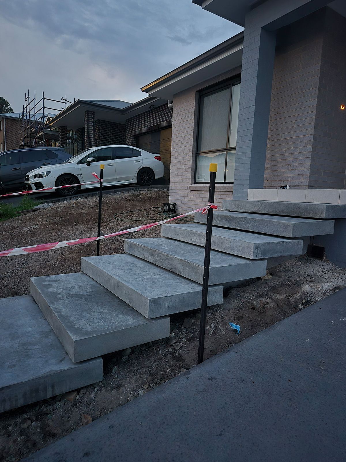Front Steps Under Construction Beside a House, With Concrete Treads and Red Caution Tape — TP Concreting In Warilla, NSW