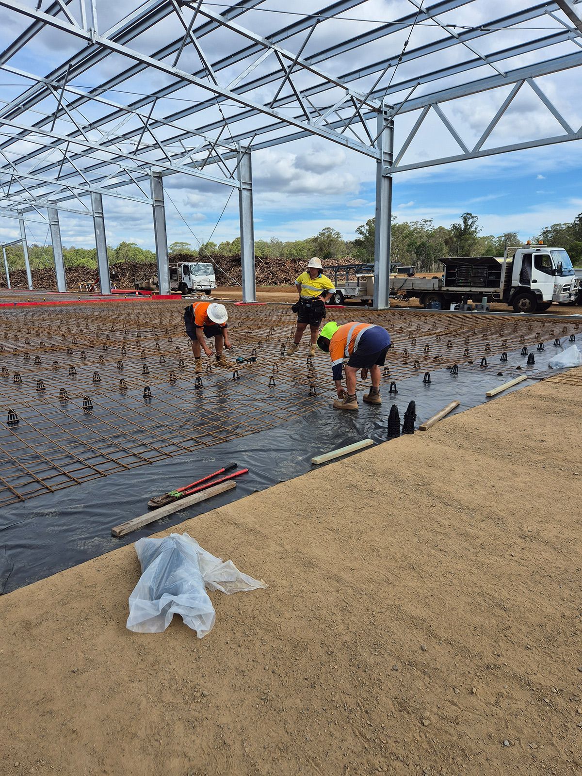 Workers Installing Flooring Inside a Large Steel-frame Building Under Construction — TP Concreting In Warilla, NSW