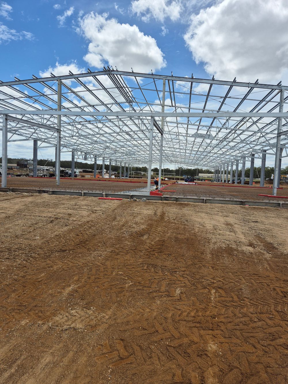 Steel Building Frame Under Construction on a Dirt Lot — TP Concreting In Dapto, NSW