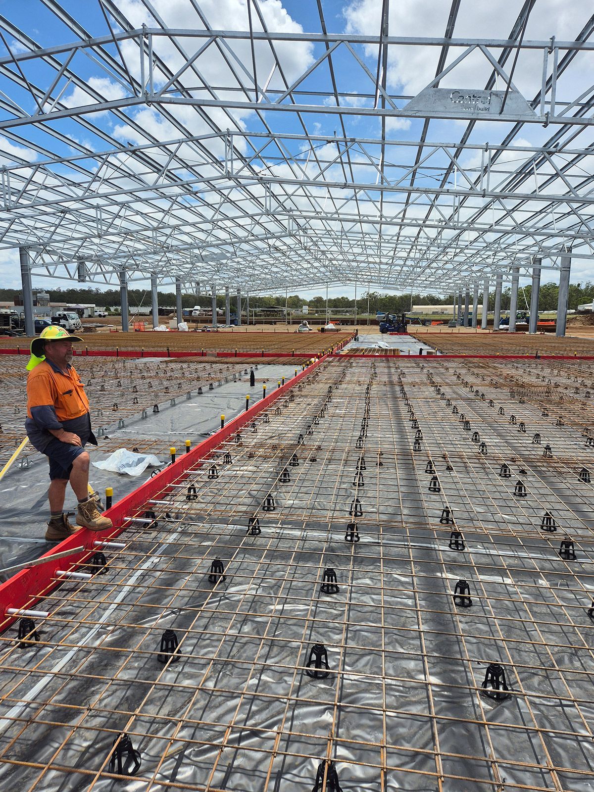 Construction Workers Laying Rebar in a Large Steel-framed Building Under Construction — TP Concreting In Warilla, NSW