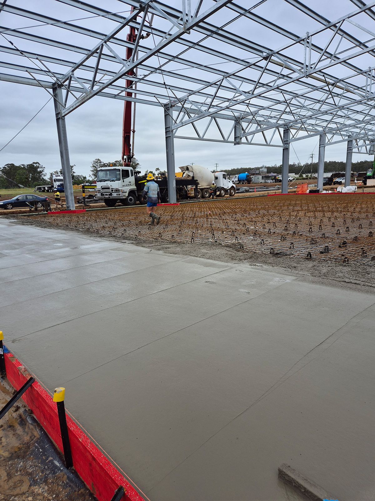 Concrete Floor Being Poured Inside a Steel-frame Building Under Construction — TP Concreting In Warilla, NSW