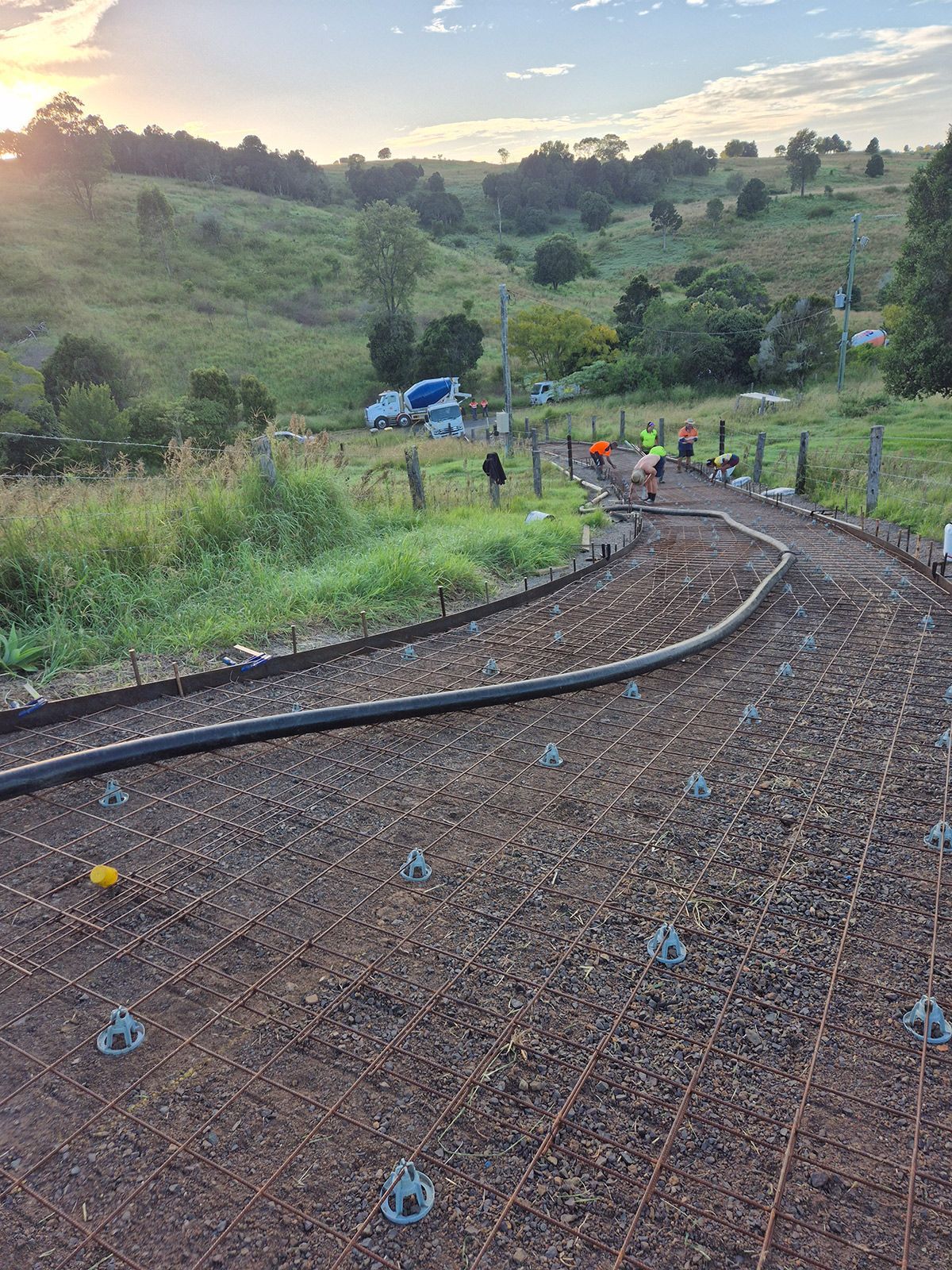 A Dirt Road Winds Through A Lush Green Field — TP Concreting In Kingaroy, QLD