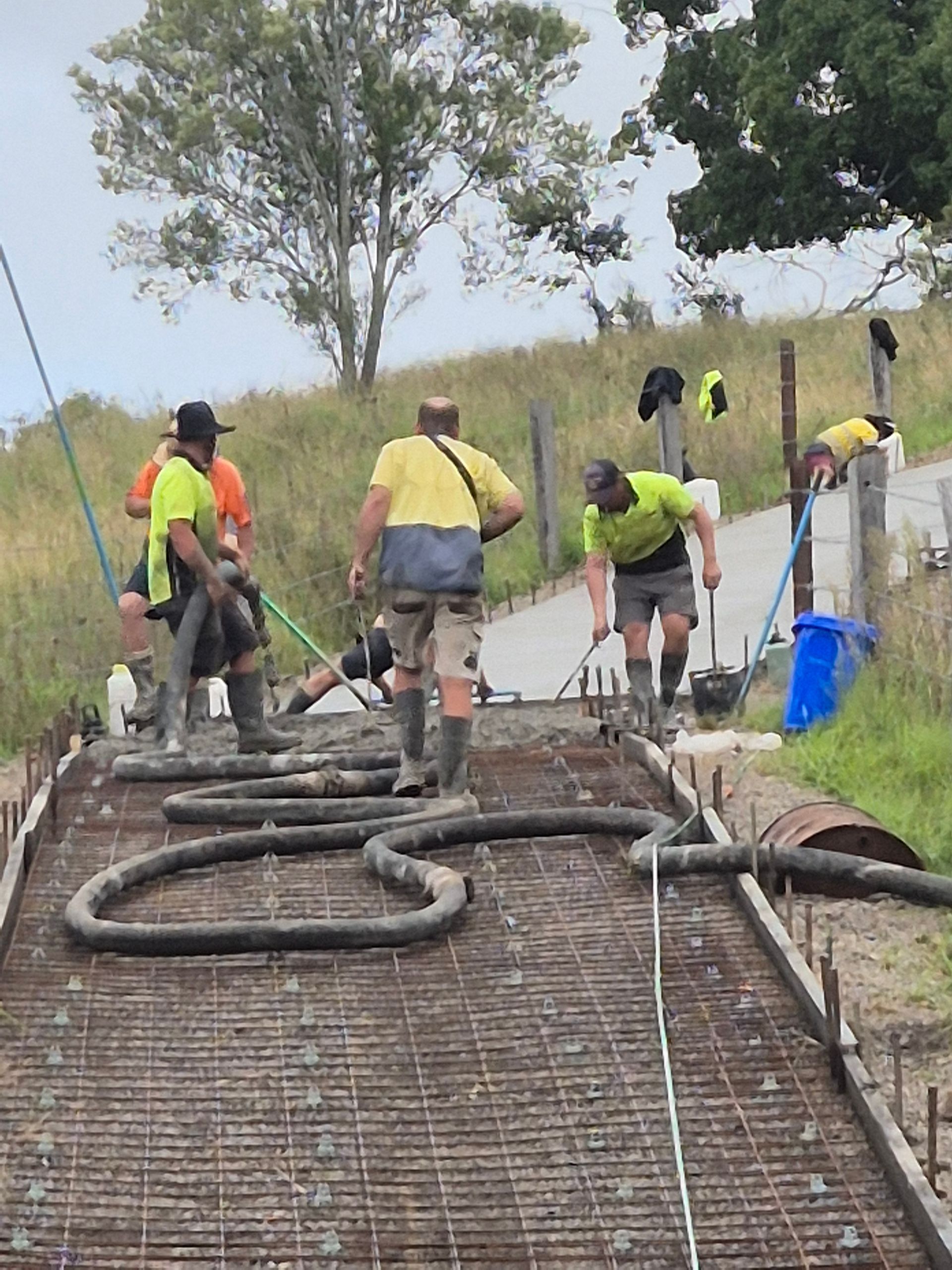 Workers in Neon Safety Vests Pour Concrete on a Rural Road Project — TP Concreting In Kingaroy, QLD