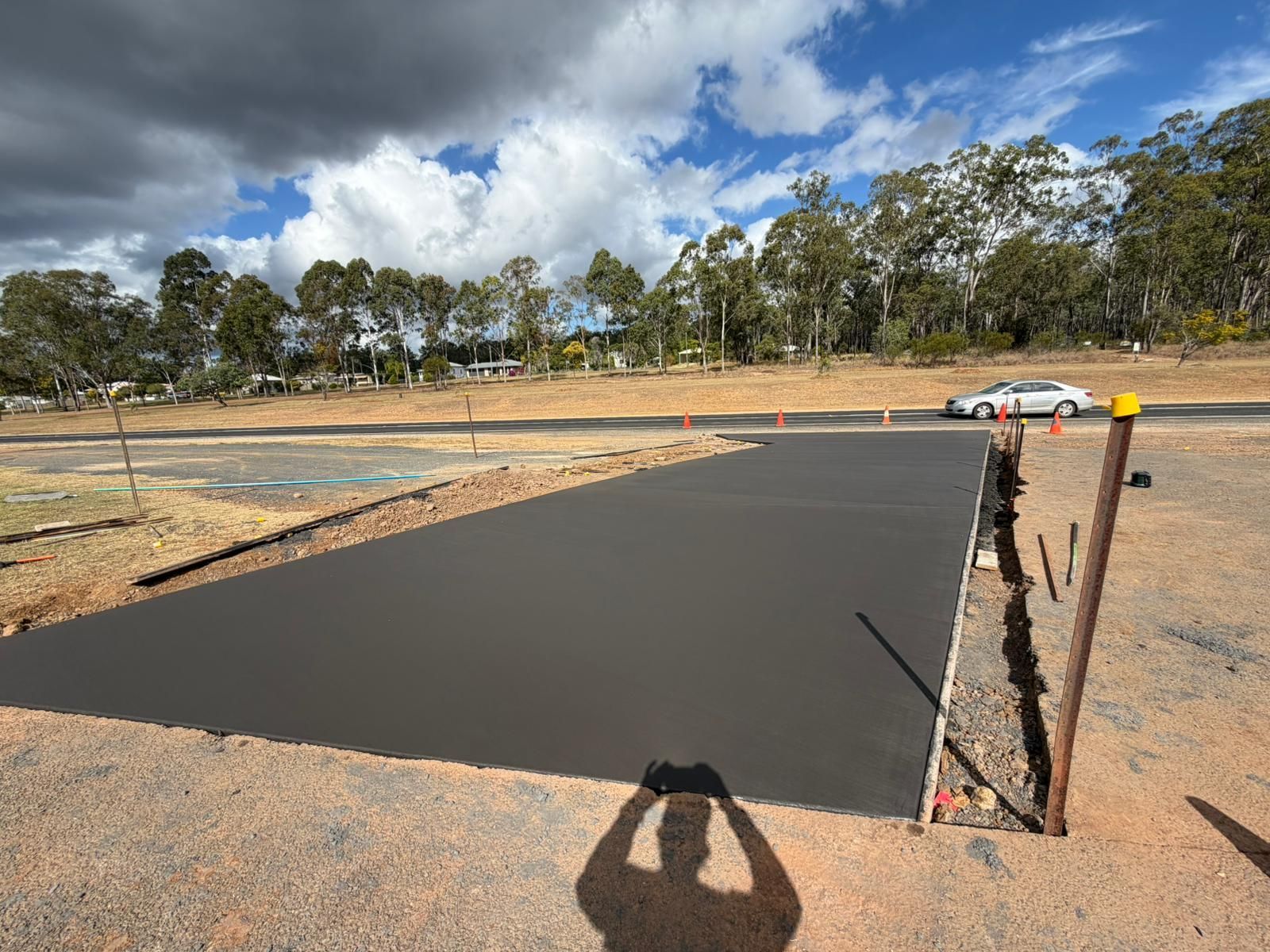 Freshly Poured Black Concrete Slab at a Roadside Construction Site — TP Concreting In Illawarra, NSW