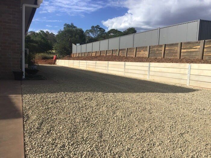 A Gravel Driveway With A Wooden Fence In The Background — TP Concreting In Warilla, NSW