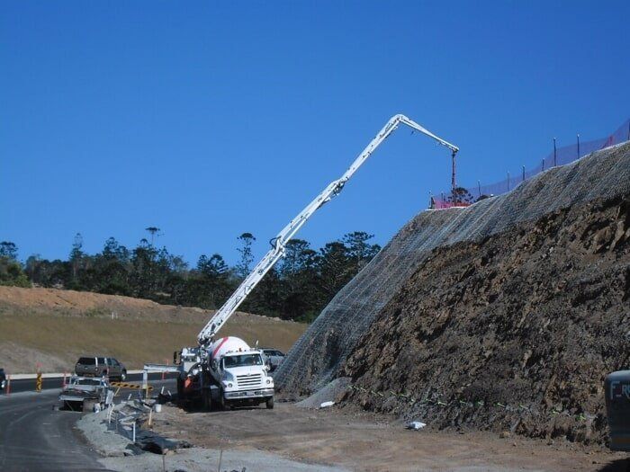 A Concrete Pump Is Being Used To Pour Concrete On A Hillside — TP Concreting In Warilla, NSW
