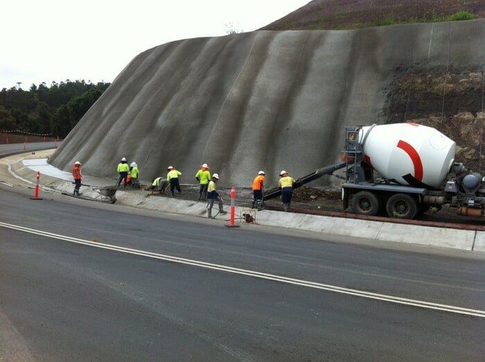 A Concrete Mixer Is Being Used To Pour Concrete On A Road — TP Concreting In Dapto, NSW