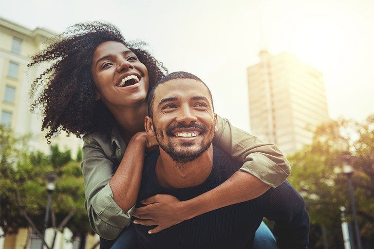 A man is carrying a woman on his back in the city.
