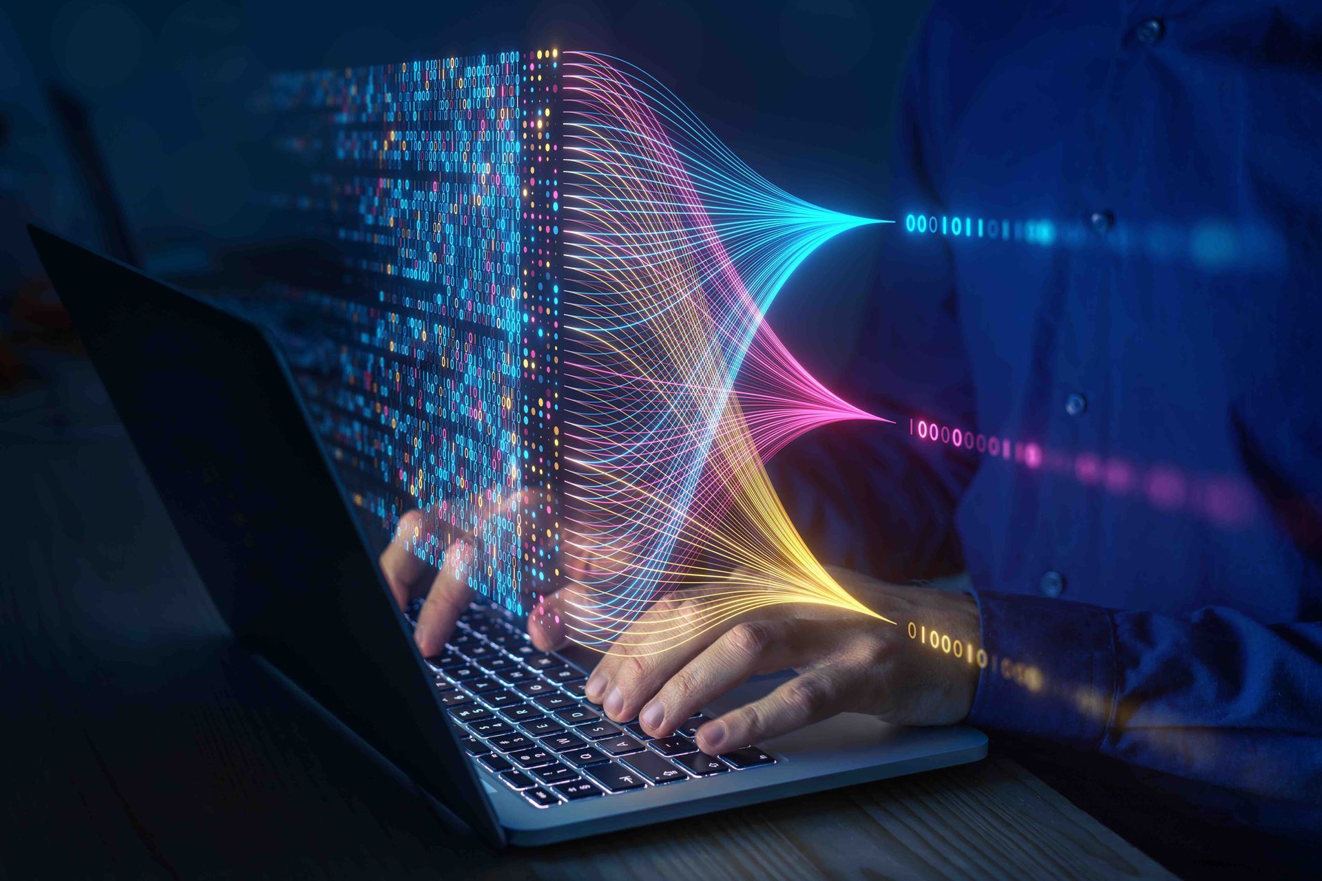 A man is typing on a laptop computer with a futuristic image coming out of it.