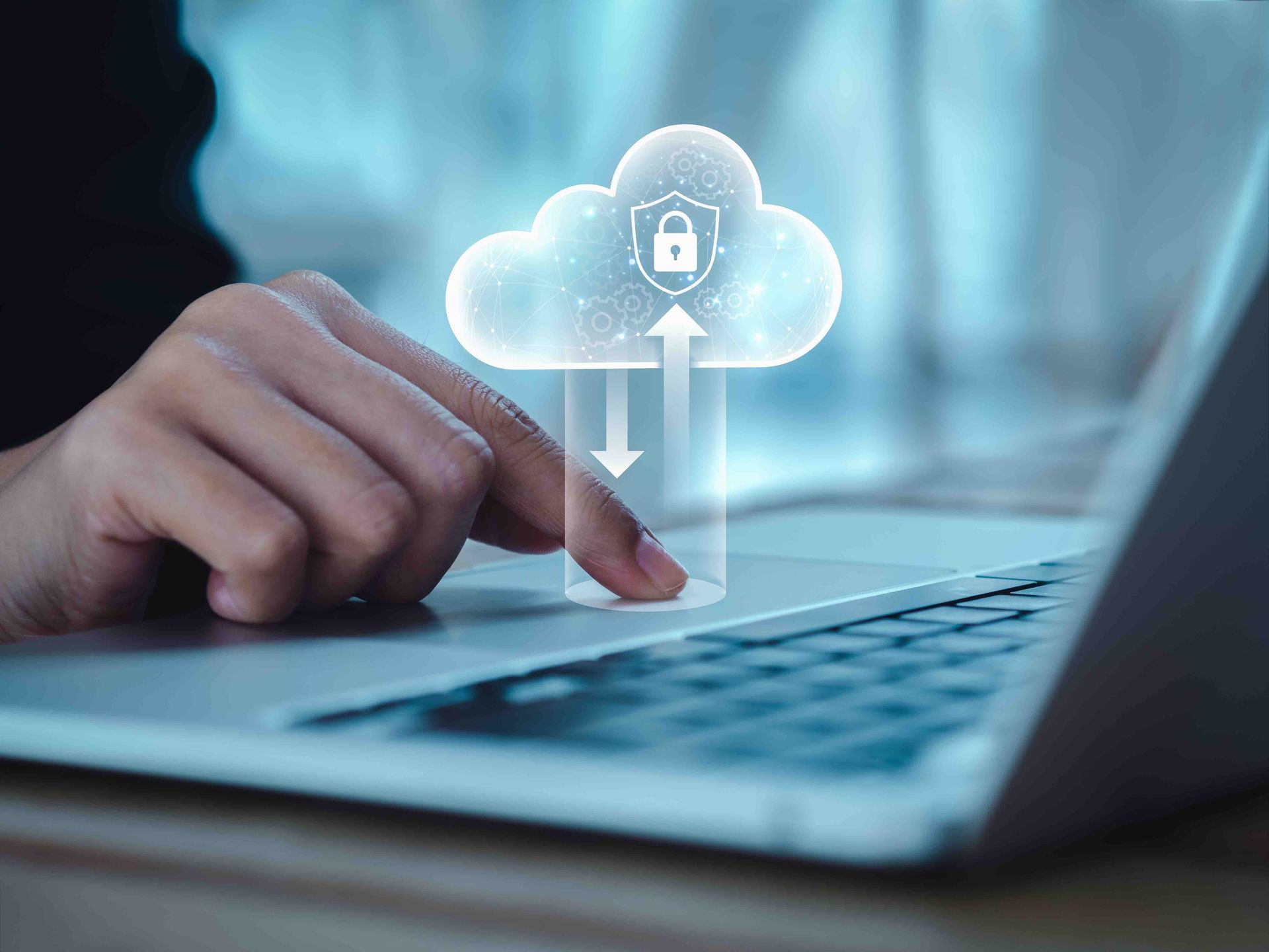 A person is using a laptop computer with a cloud icon on the screen.