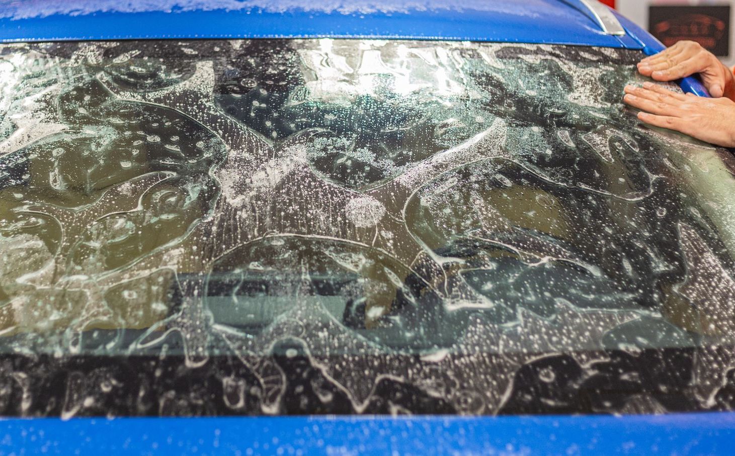 A person is putting a film on the windshield of a car.