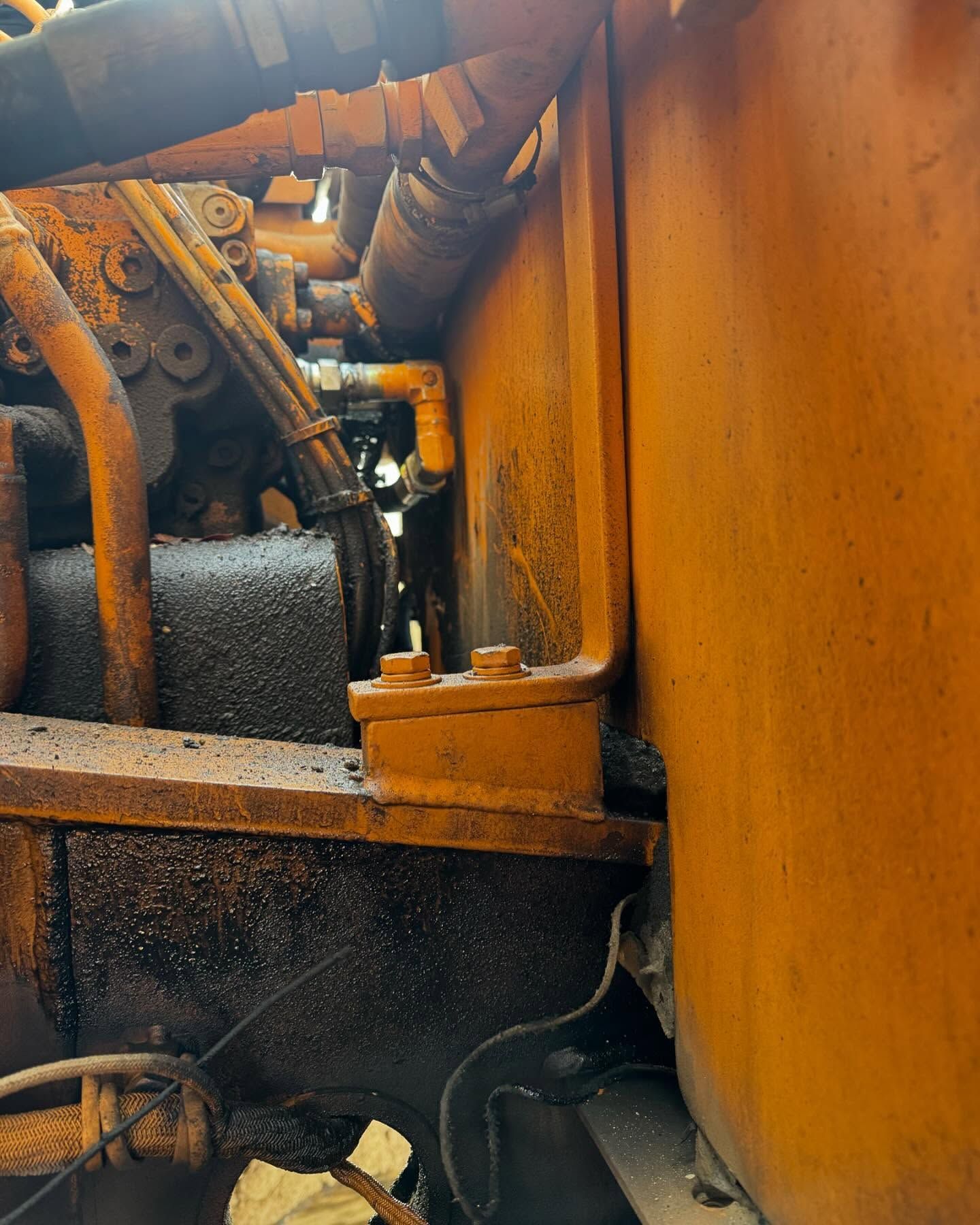 Rusty industrial machinery with pipes, bolts, and a large orange metal panel close-up.