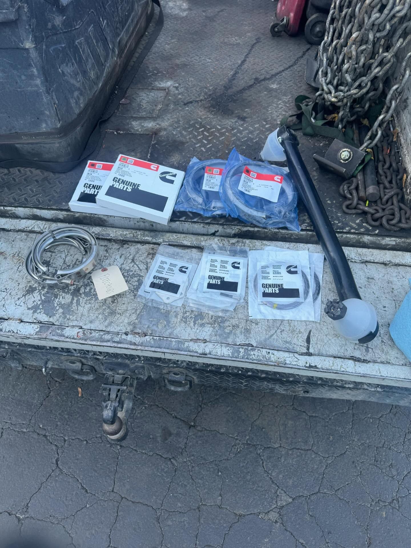 Truck tailgate with chains, ropes, and packaged hardware laid out on a worn metal surface.