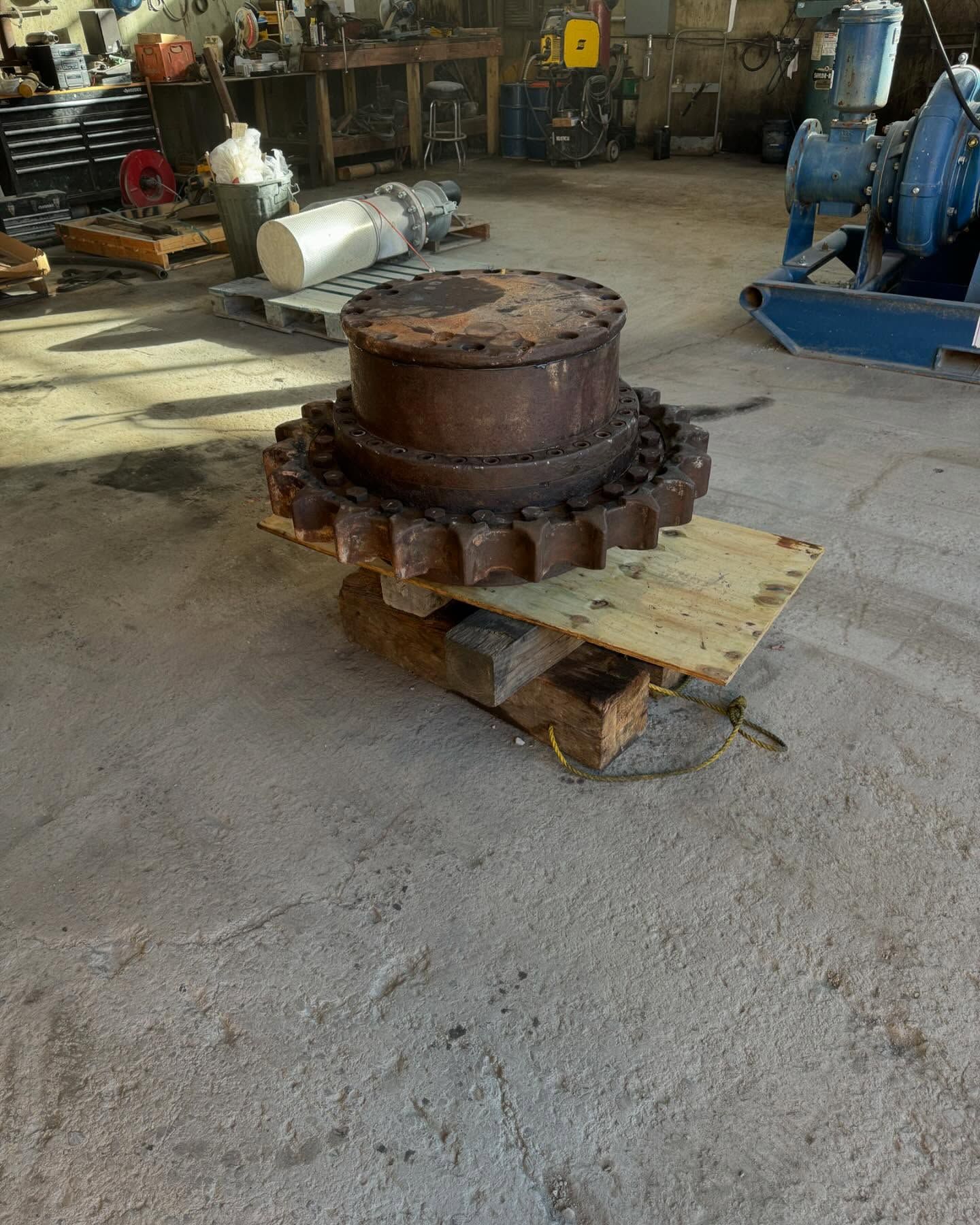 Rusty industrial gear assembly on a wooden pallet in a workshop garage