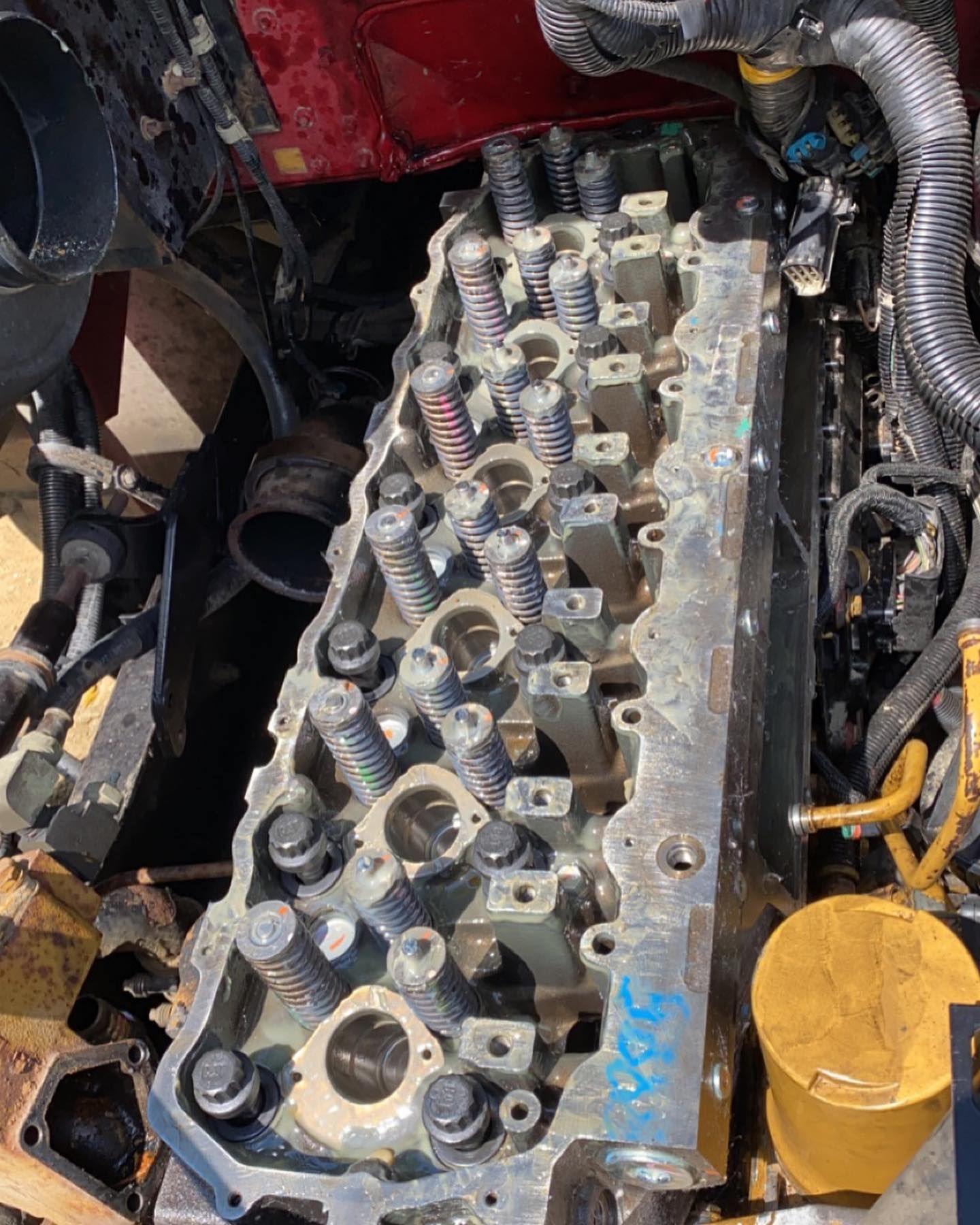 Open engine cylinder head with visible valves and hoses in a workshop setting