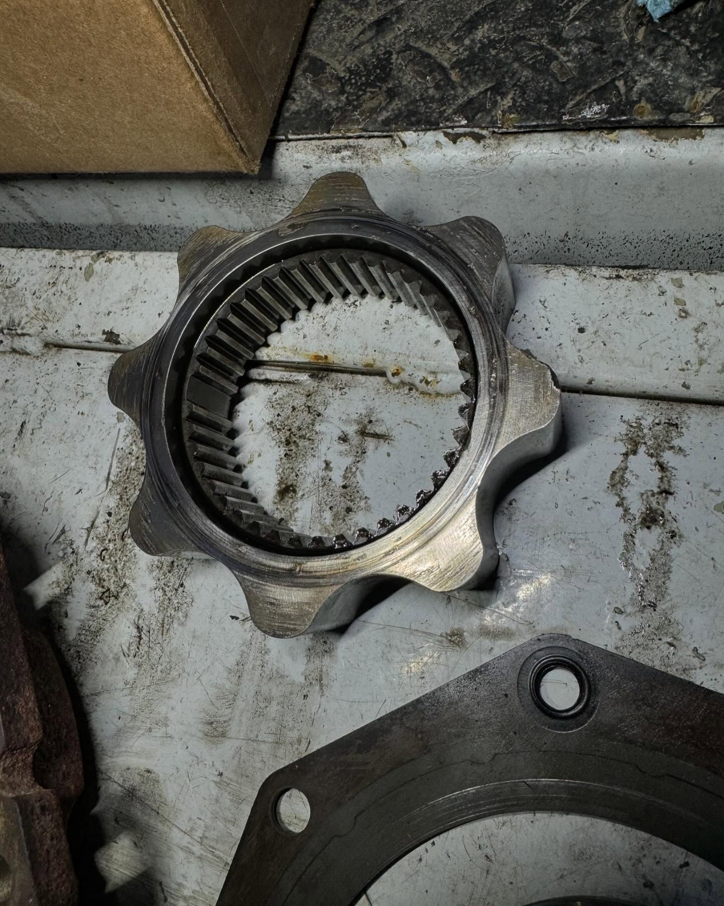 Close-up of a dirty metal star-shaped coupling with inner splines on a workbench.