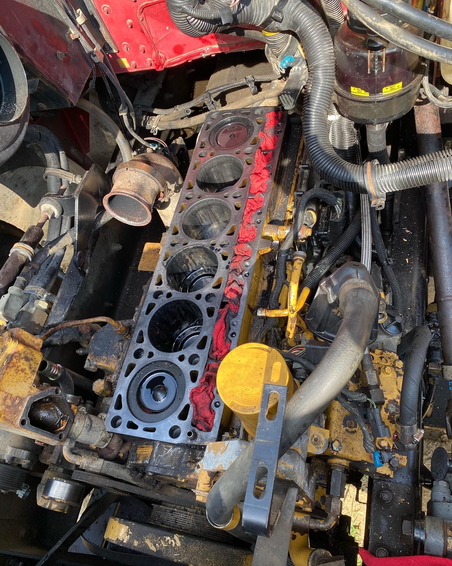 Close-up of a damaged car engine with the cylinder head removed, showing exposed pistons and red gasket sealant.