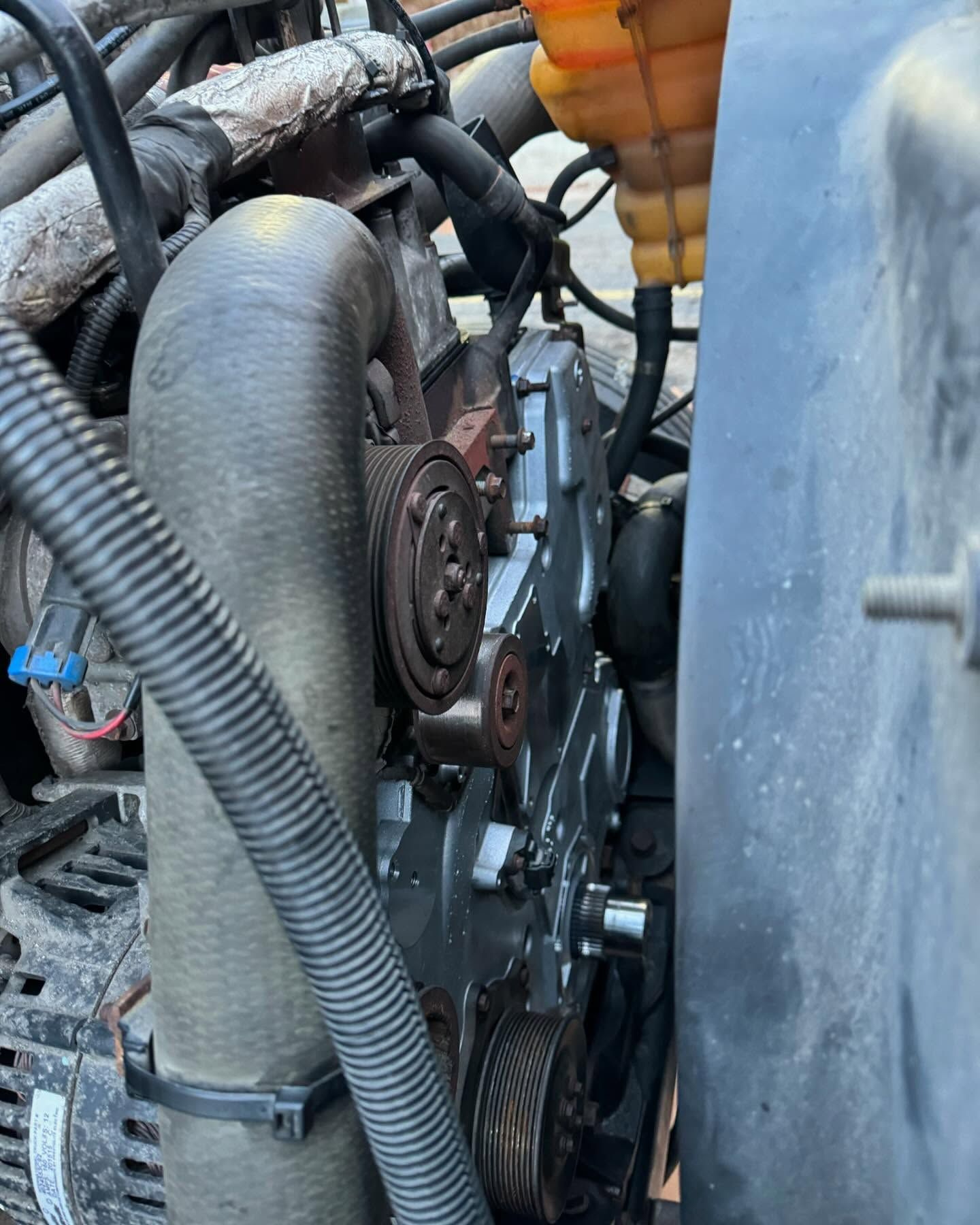 Close-up of an engine compartment with belts, hoses, and metal components.