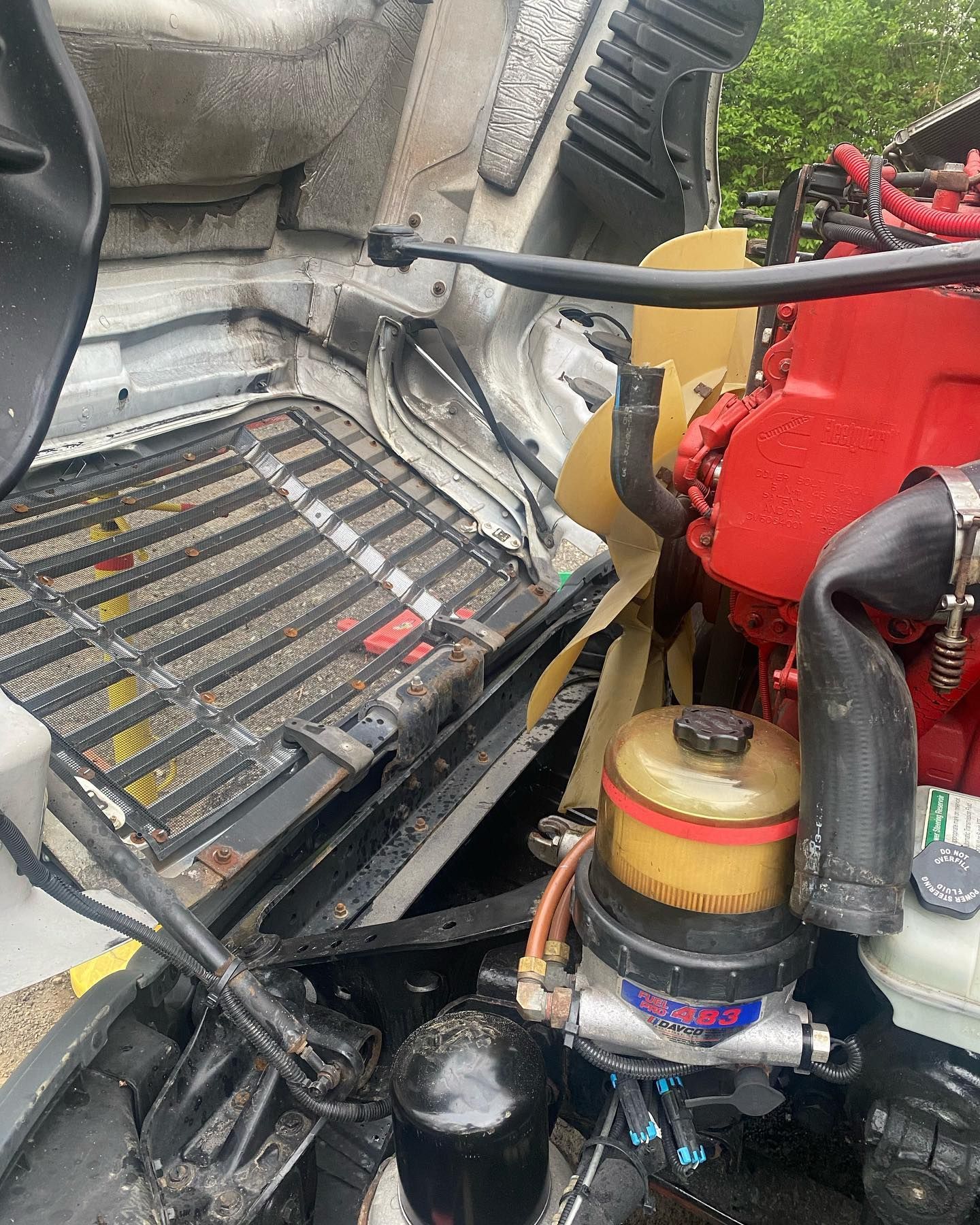 Close-up of a red engine compartment with hoses, filter, and metal grille in a vehicle interior