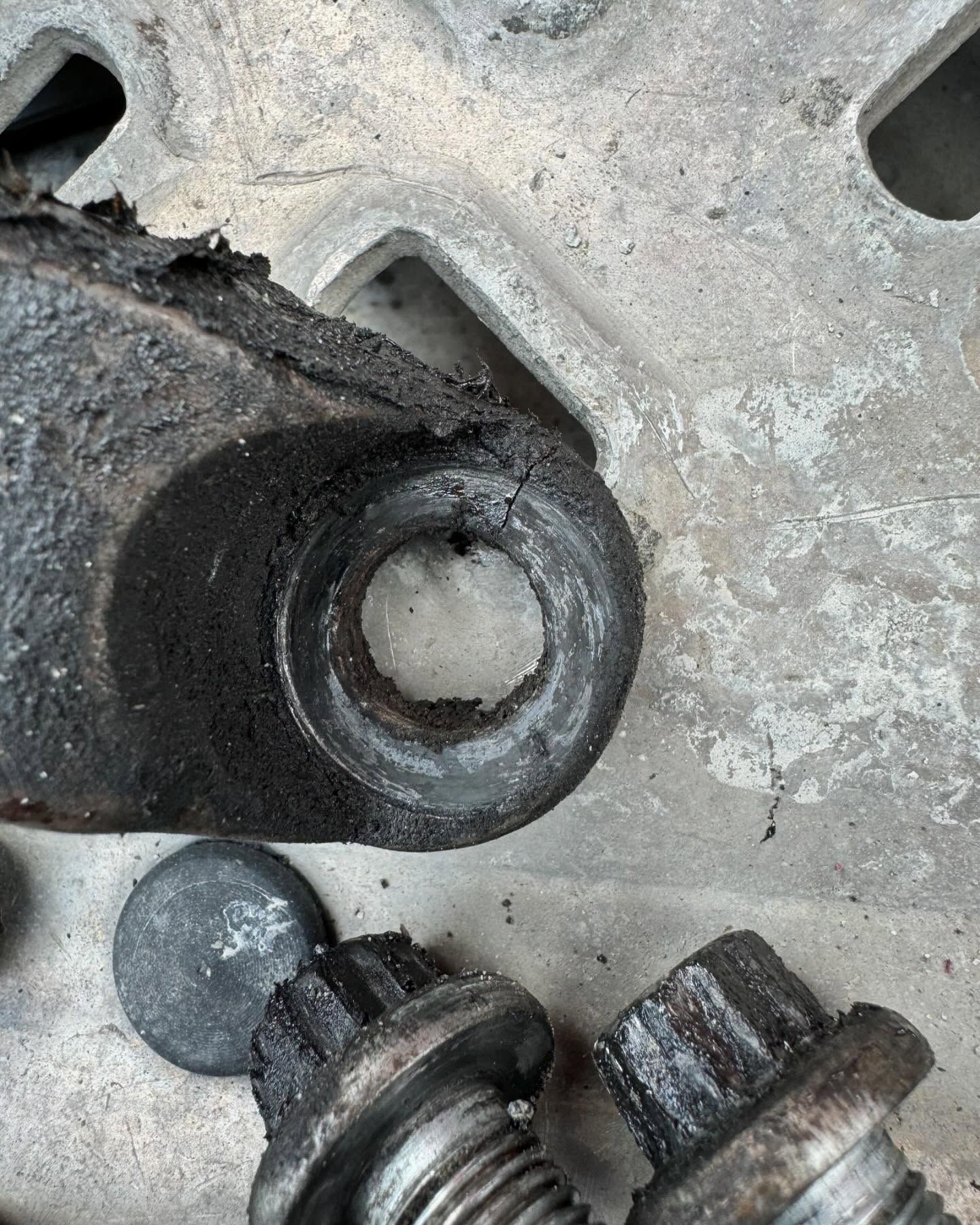 Close-up of two worn metal parts with circular holes on a concrete surface.