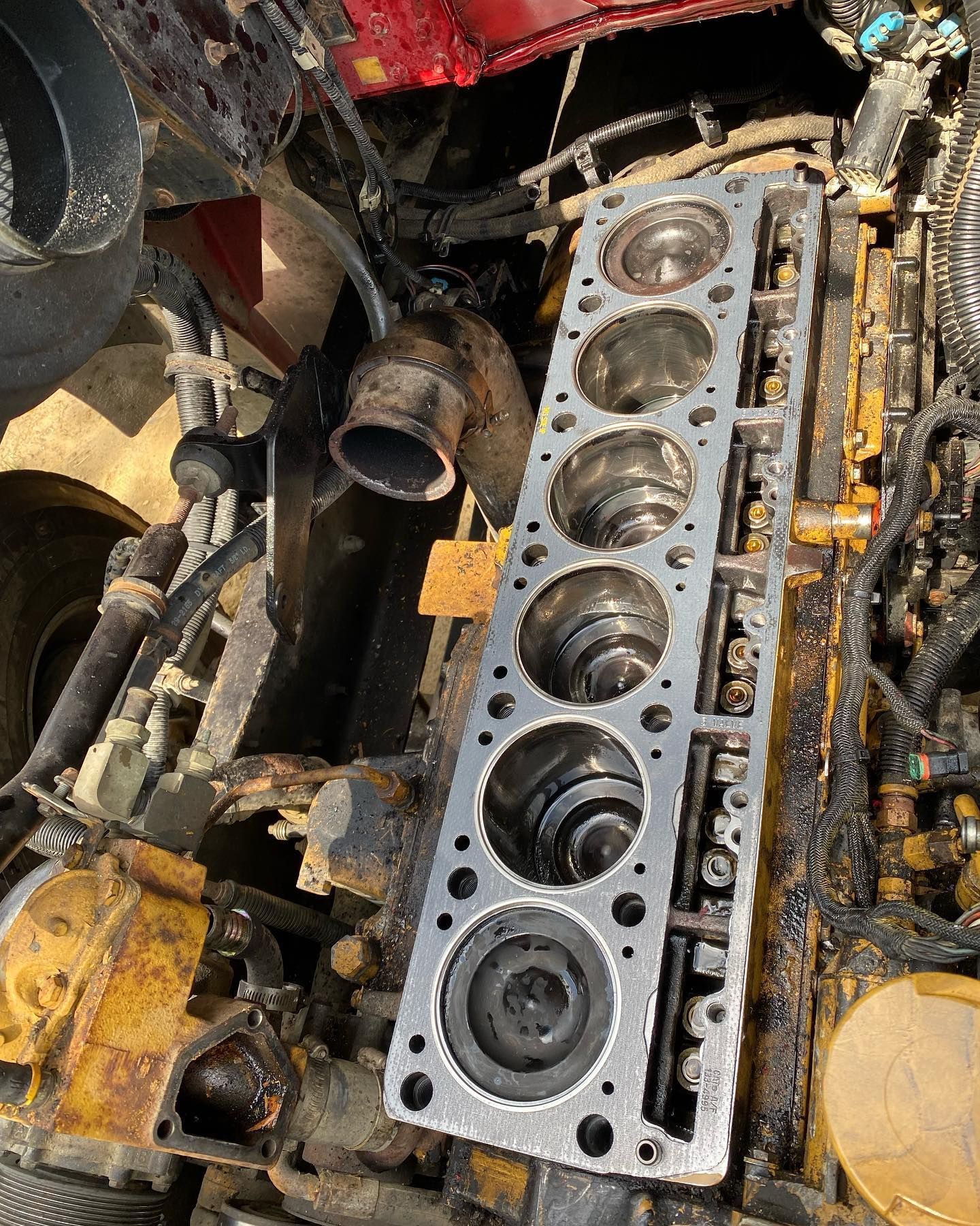 Disassembled engine block with exposed cylinders and rusted machinery parts in a workshop.