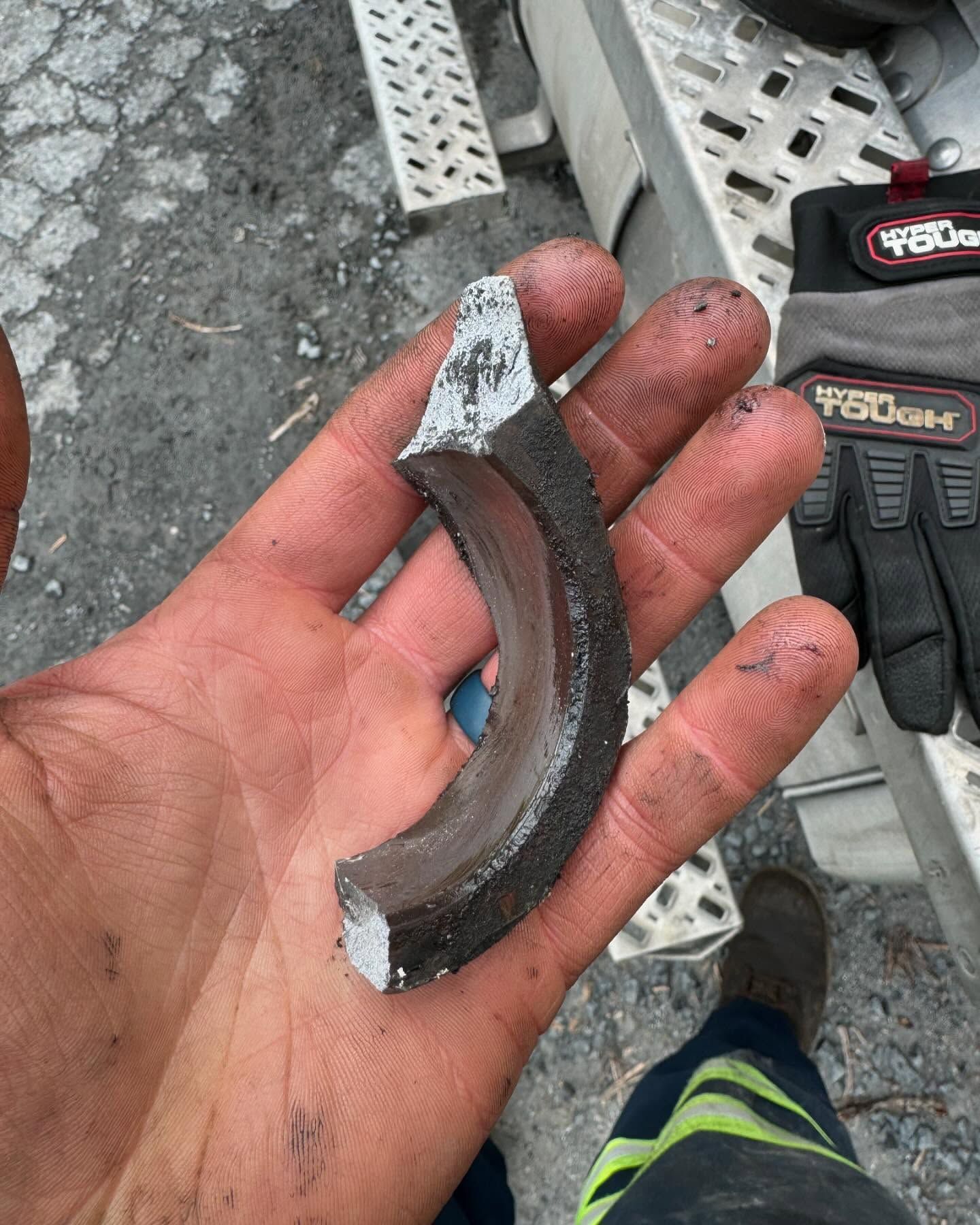 Dirty hand holding a broken metal ring on a construction site.