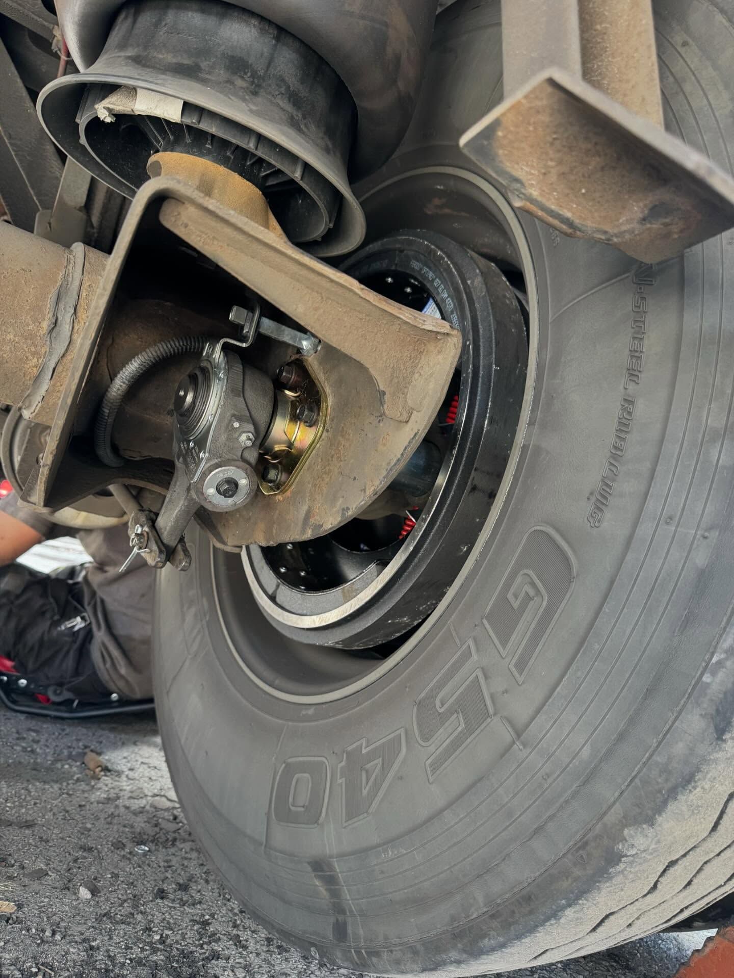 Close-up of a truck wheel assembly with exposed suspension and a dusty tire.