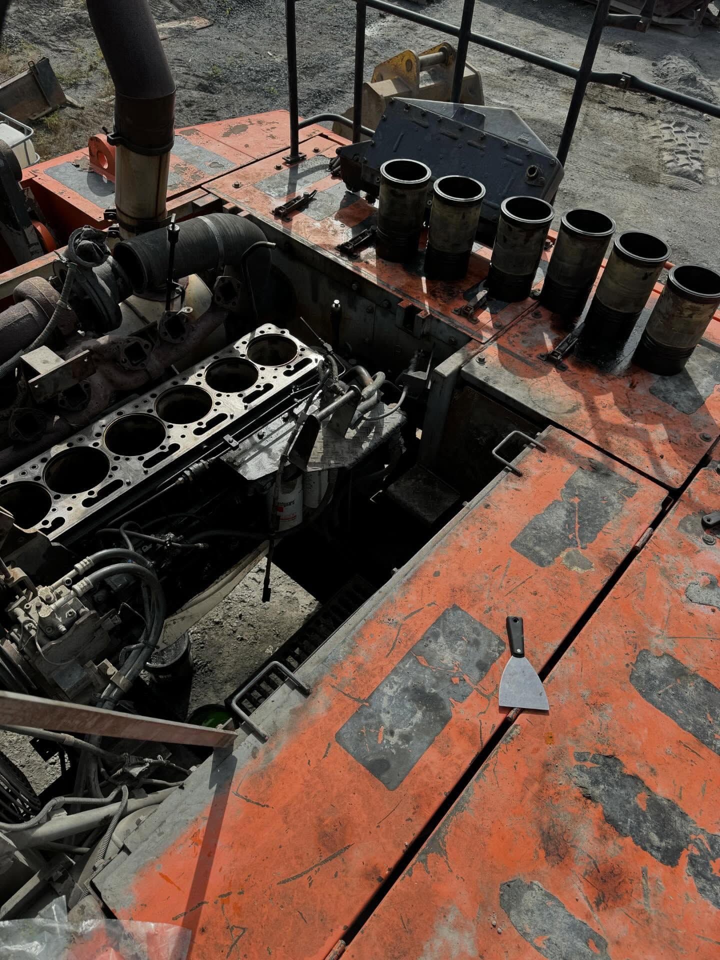 Charred engine compartment on an orange boat deck, with blackened parts and several metal pipes nearby